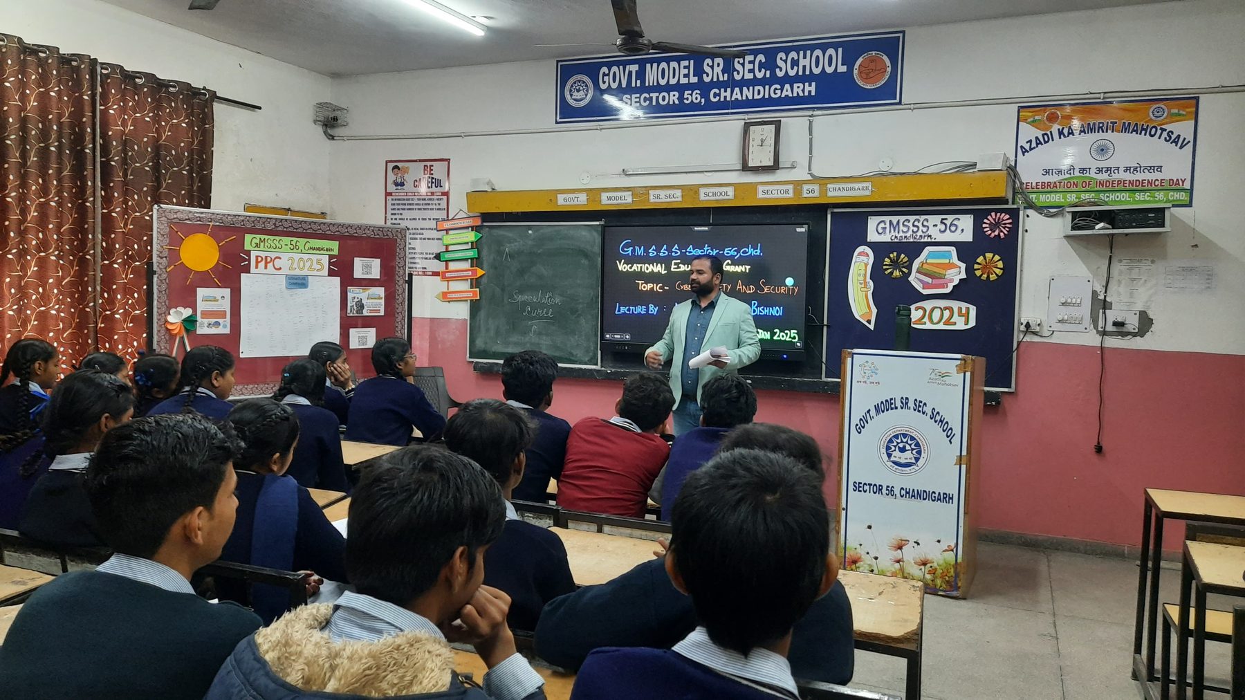 Manu addressing a full classroom